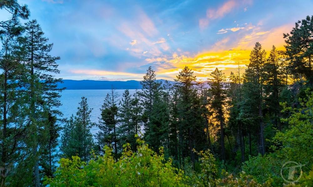 A scenic, colorful view of Flathead Lake is captured at sunset, showcasing gate beauty of the Montana landscape